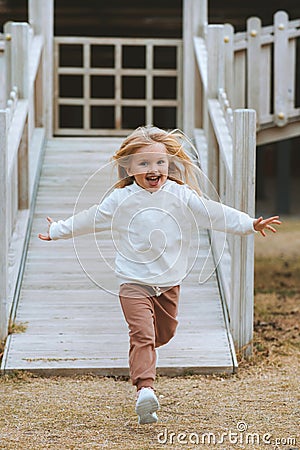 Child running on the playground girl playing games kid 4 years old happy emotions Stock Photo