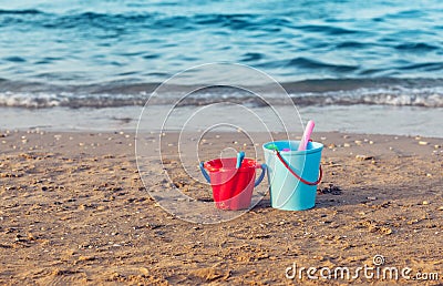 Child`s bucket, spade and other toys on empty beach Stock Photo