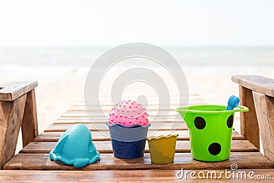 Child`s bucket, spade and other toys on tropical beach against blue sky Stock Photo