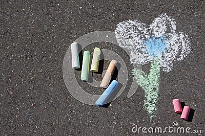 Child`s drawing of flower and colorful chalks on a street. Stock Photo