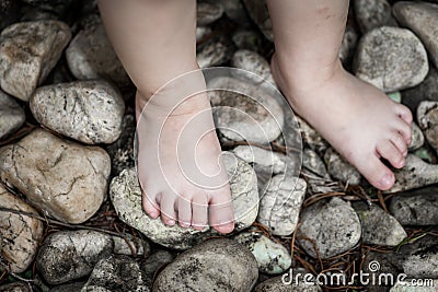 Child's foot learns to walk on pebbles, reflexology massage Stock Photo