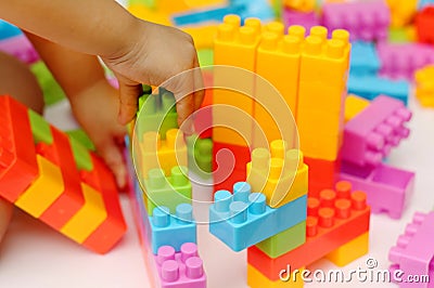 Child`s hand building plastic toy blocks with blurred background Stock Photo