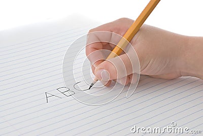 Child's hand holding pencil, writing alphabet on paper Stock Photo