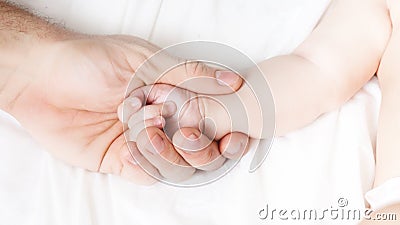 a child`s hand lies in a man`s hand. dad holds the baby`s hand. happy family concept. paternal love Stock Photo