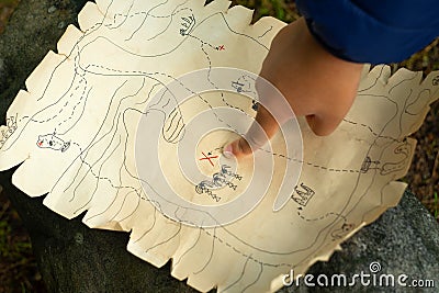 A child& x27;s hand points to the place where the treasures are buried. Active games for children. In search of a pirate Stock Photo