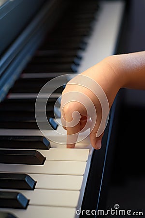 A kid hand presses the piano keys. Early musical development in young children Stock Photo