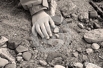 Child's Hand on Sand and Stones Stock Photo