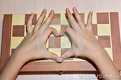 The child`s hands on the chessboard show the heart and love of playing chess Stock Photo