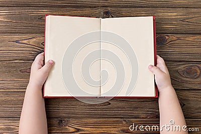 The child`s hands hold an open book with clean sheets of pages. Stock Photo