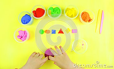 Child`s hands made colored geometric shapes . Yellow background. Masterclass for school and kindergarten. Stock Photo