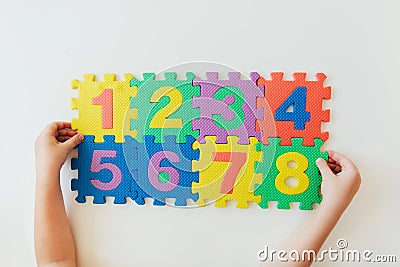 Child`s hands playing with numbers, learning simple multiplication. Colorful bright puzzle numbers on white background, education Stock Photo