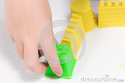 A child`s hands playing with yellow magic sand and building, kne Stock Photo