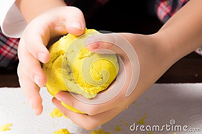 A child`s hands playing with yellow magic sand and building, kne Stock Photo