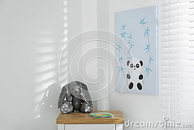 Child`s room with chest of drawers, toy bunny and cute poster on wall Stock Photo