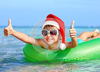 Child in santa hat floating on inflatable ring. Stock Photo