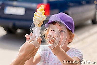 Child, school age girl receiving a large tasty ice cream cone. Sugar, sweets, children and ice-cream simple concept, outdoors Stock Photo