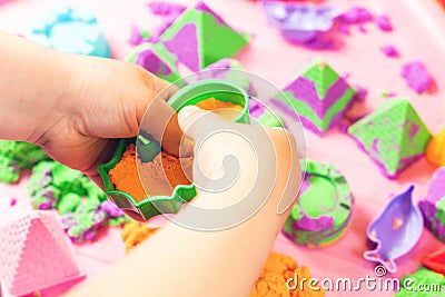 The child sculpts figures from multi-colored kinetic sand, developing fine motor skills of hands Stock Photo