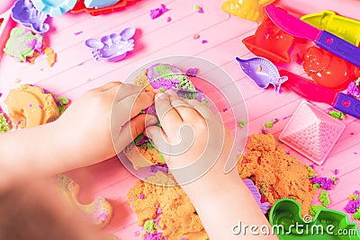 The child sculpts figures from multi-colored kinetic sand, developing fine motor skills of hands Stock Photo