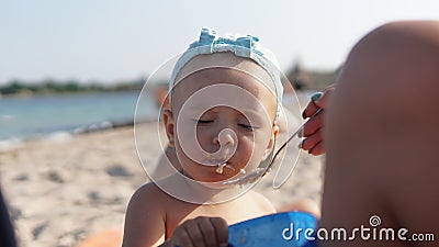 Child on sea beach eating porridge. Sea coastline on background Stock Photo