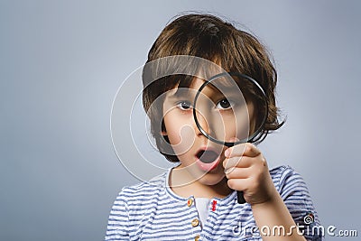 Child See Through Magnifying Glass, Kid Eye Looking with Magnifier Lens over Gray Stock Photo