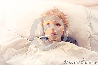 Child sick in bed with fever and thermometer Stock Photo