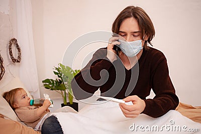 The child is sick, the father in a mask checks the temperature of his daughter. Influenza, cold, coronavirus, covid, home Stock Photo