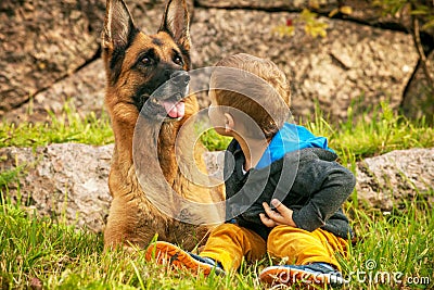 Child sits turning with a German shepherd in nature Stock Photo