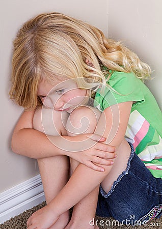 Child sitting in corner Stock Photo