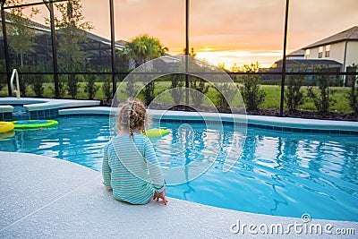 Child sitting on the edge of a swimming pool on a warm summer day Stock Photo