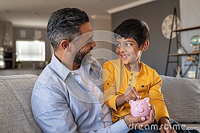 Child sitting on father lap while saving money Stock Photo