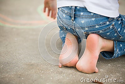 Child sitting on feet on driveway Stock Photo