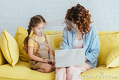 Child sitting near young babysitter working Stock Photo