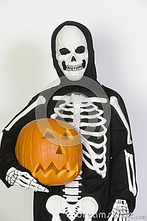 Child In Skeleton Costume Holding Jack-O-Lantern Stock Photo