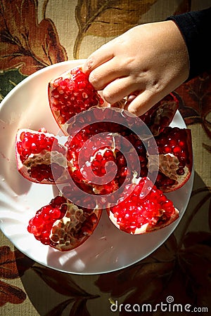 Child is snacking on a juicy ripe pomegranate Stock Photo