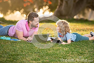 Child son with father learning outdoor by studying online and working on laptop. Stock Photo