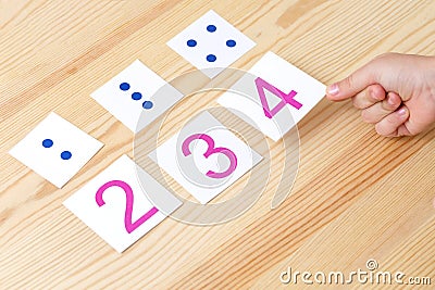 The child spreads cards with numbers to cards with dots. The study of numbers and mathematics Stock Photo