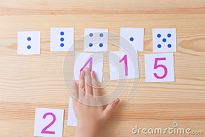The child spreads cards with numbers to cards with dots. The study of numbers and mathematics Stock Photo