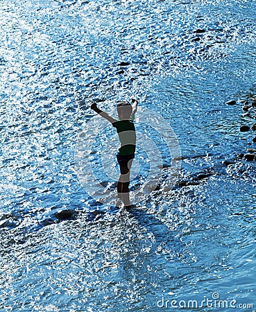 Child standing in water sparkling in backlight Stock Photo