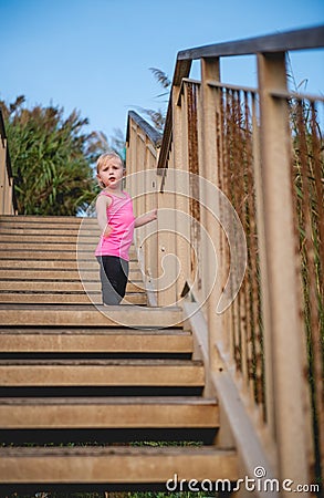 Child standing on wooden steps at beach looking down Stock Photo