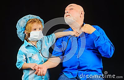 Child with Stethoscope play doctor with grandpa. Kid boy doctor playing with grandfather. Boy in doctor mask. Treatment. Stock Photo