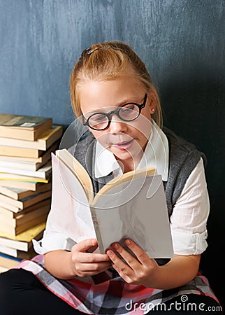 Child, student reading book and chalkboard for education, language learning and knowledge in classroom. Smart girl or Stock Photo