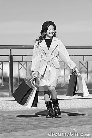 Child stylish hold bunch shopping bags. Girl cute little lady coat and beret carry shopping bags. Spring shopping Stock Photo