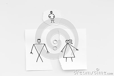 Child suffers from a divorce. Torn sheet of paper with drawn man, woman and child, wedding rings between parts on white Stock Photo