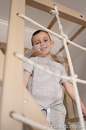 a child on the Swedish wall plays sports at home, a boy climbs a ladder, the concept of sports and health Stock Photo