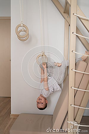 a child on the Swedish wall plays sports at home, a boy climbs a ladder, the concept of sports and health Stock Photo