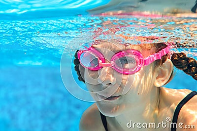 Child swims in pool underwater, happy active girl in goggles has fun in water, kid sport on family vacation Stock Photo