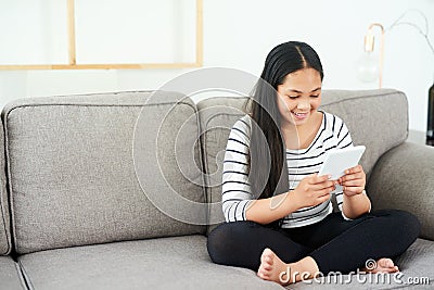 Child, tablet and couch in home with elearning, online education and upskill app game. Living room, tech and digital Stock Photo