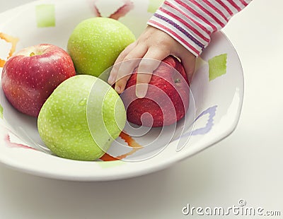 Child taking apple from bowl Stock Photo