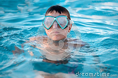 A child, a teenager in a swimming mask swims in clear blue water in a pool, pond or ocean, close-up Stock Photo