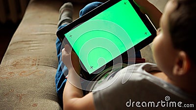 Child tilting to the left a tablet PC with green screen, back view Stock Photo